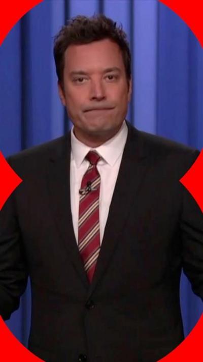 Jimmy Fallon in a black suit with a maroon and white striped tie