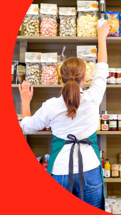 An anonymous woman, photographed from behind, stocking supermarket shelves