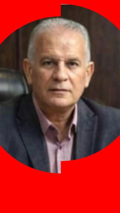 A man with short grey hair wears a dark suit jacket and looks at the camera