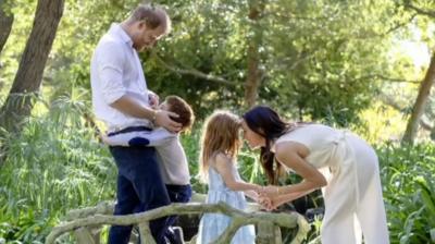 Prince Harry and his wife and children pose in a sunlit garden