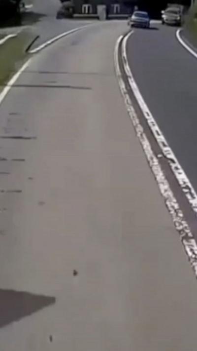 A car in the distance on the wrong side of the road coming up to a corner with a car coming the other way