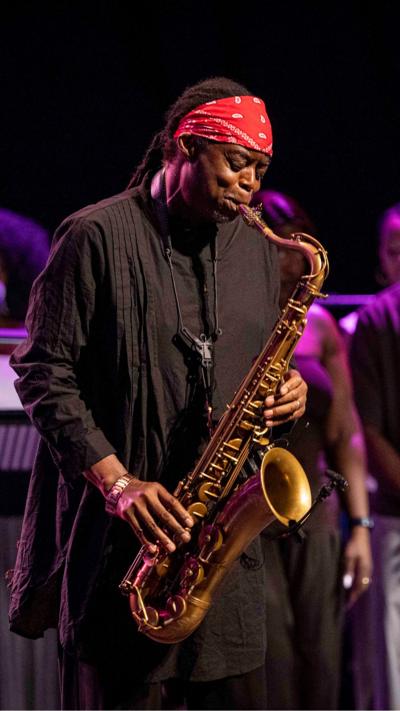 Live jazz saxophonist performing on stage wearing a red bandana, playing tenor saxophone at a concert event.