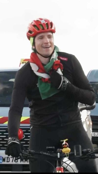 Greg James cycling with a Welsh flag around his neck