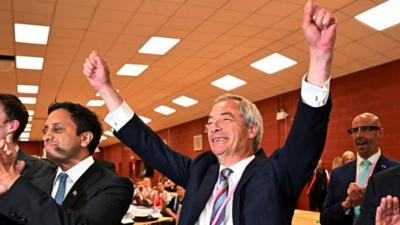 Nigel Farage raises his hands in the air