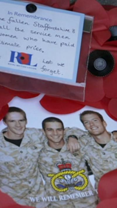 A wreath of red poppies with a photograph of three soldiers and a Lest We Forget message