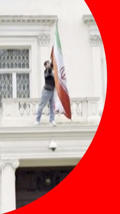 Man who has climbed on Iranian embassy building grabs flag