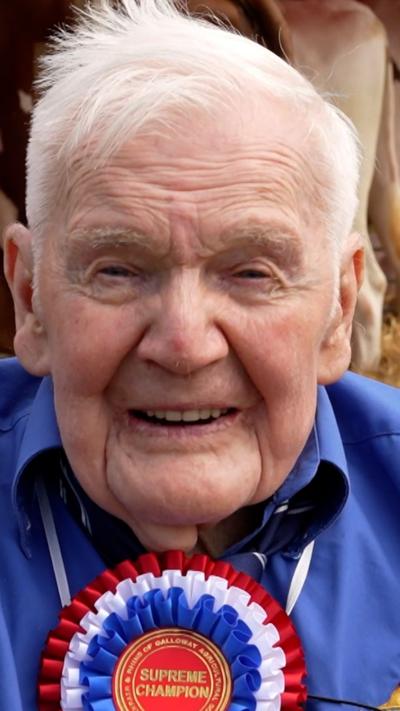Jackie Brown - an elderly man with white hair, wearing a blue shirt and rosette reading "Supreme Champion"
