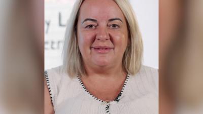 A blonde woman with bobbed hair smiles at the camera