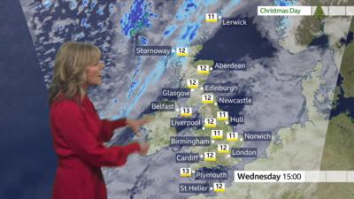 Weather forecaster standing in front of map of UK showing temperatures for 15:00 on Christmas Day