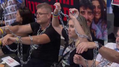 People sitting with chains around them, on the ground outside Benjamin Netanyahu's office