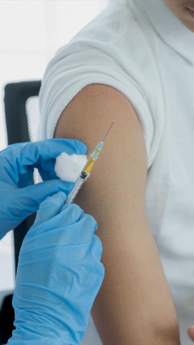 A person in blue gloves preparing an injection 