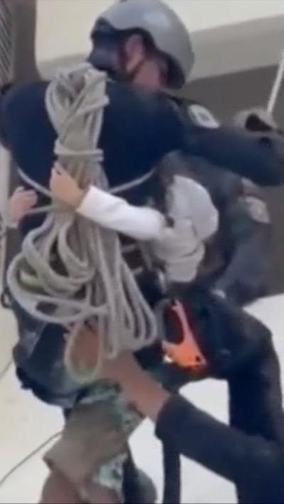 Man with a child wrapped around him exiting a building with a harness.