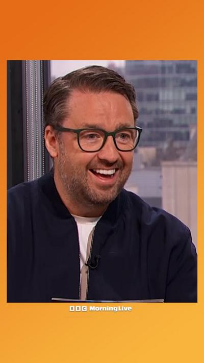 Jason Manford in the Morning Live studio wearing a navy blue jacket over a white t shirt.