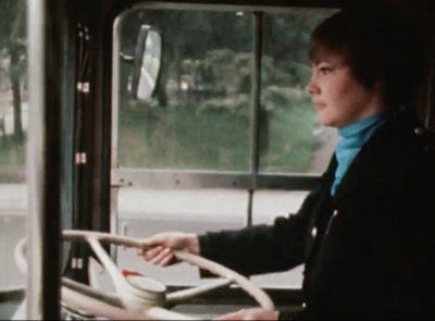 Sandra Holt the UK's first female bus driver holds steering wheel of bus