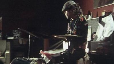 Ian Dury sits at a drumkit
