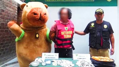 A police officer in a capybara costume poses with an alleged drug dealer who has been arrested