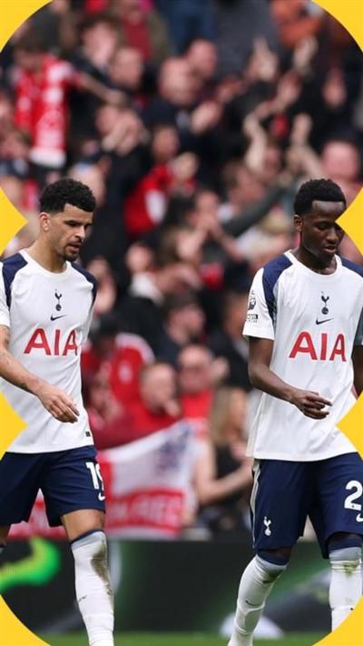 Two Spurs players walk across the pitch with their heads slightly bowed
