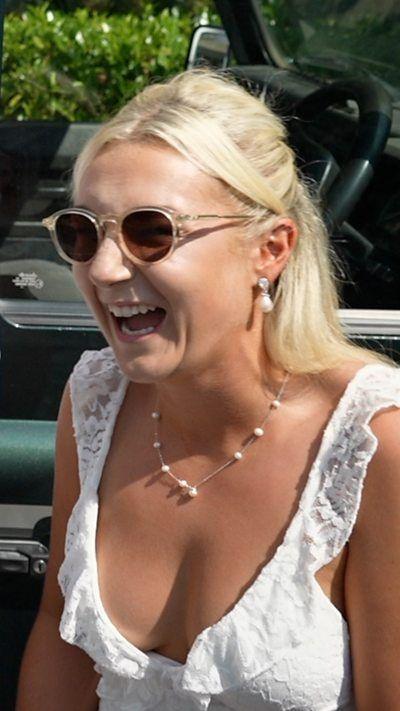 A blonde woman wearing a white shirt and sunglasses.