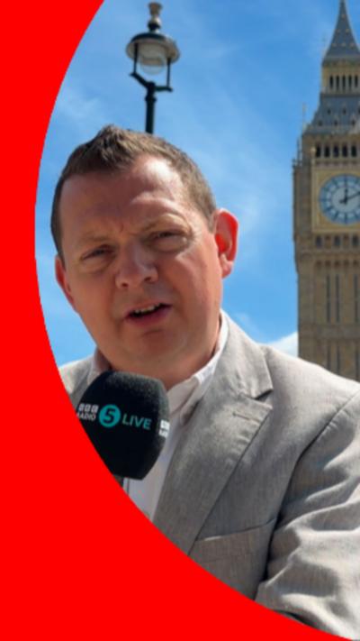 Matt Chorley is wearing a light grey suit with a white shirt. He is holding a microphone.
© BBC