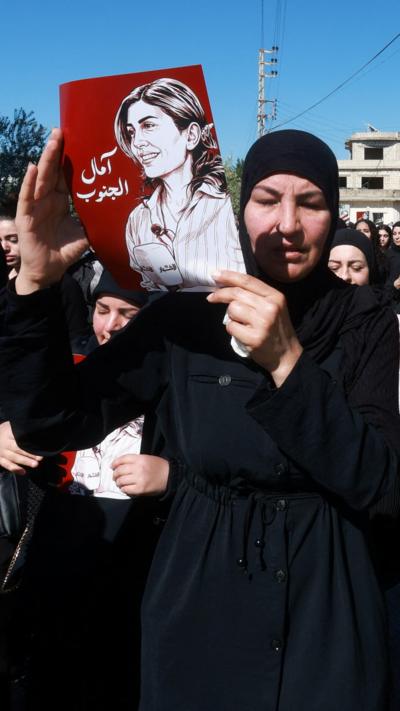 A woman holds up a picture of journalist Amal Khalil at her funeral