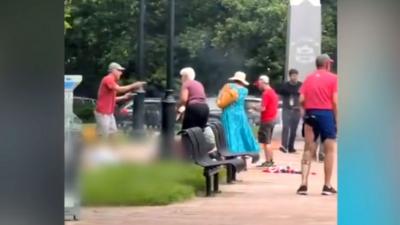 People helping others on the ground in Colorado park with suspect standing nearby watching
