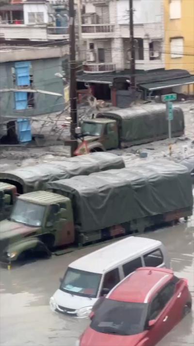 Water surrounds a dark green truck up to its bonnet on a city street in Taiwan.