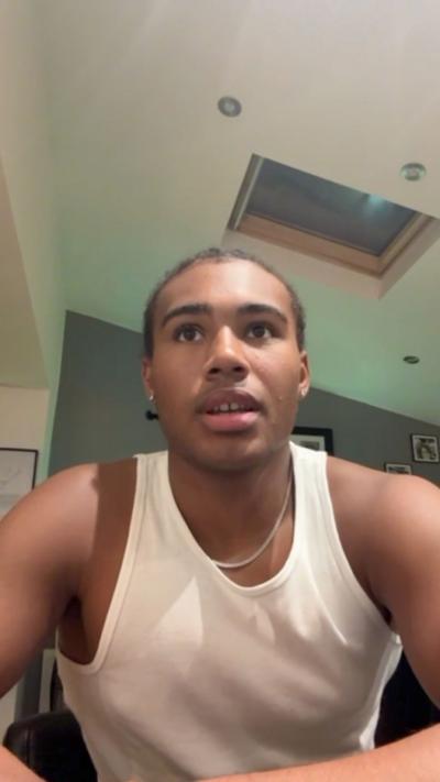 Selfie style photo of a man in a white vest top sitting down