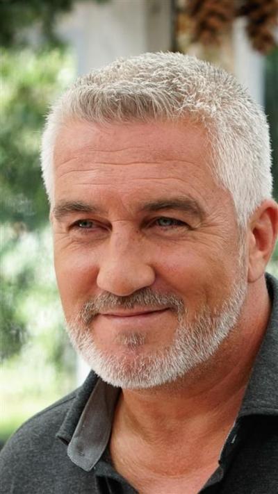 A man with silver stubble smiles at something off camera