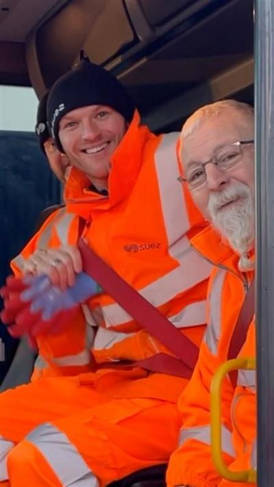Refuse collectors smile at the camera in bright orange uniform