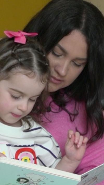 A woman in a pink jumper holding a young child
