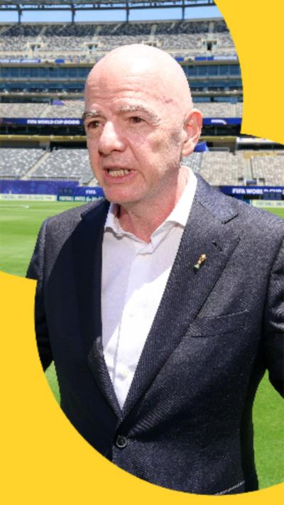Gianni Infantino wears a dark suit with a white shirt. He has his hands raised in front of him.