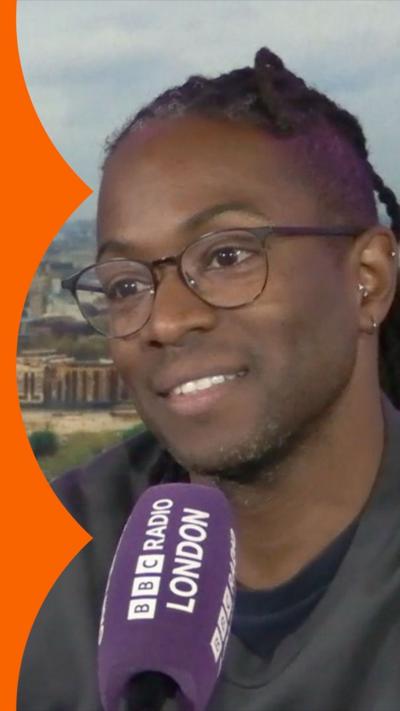 TV presenter Nigel Clarke sits in front of a purple Radio London branded microphone in a studio.