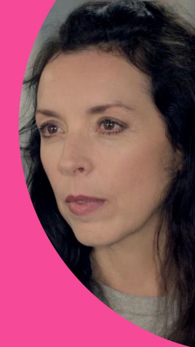 A woman looks annoyed. She has long brown hair.