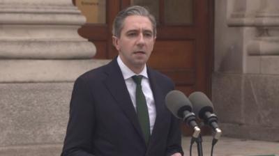 Simon Harris standing in front of microphones 