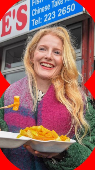 Green MP Hannah Spencer wears a pink and blue scarf while eating chips and curry sauce.
