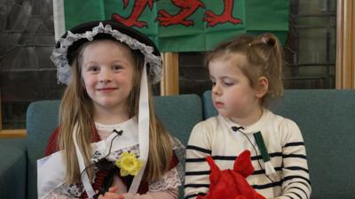 A little girl in a traditional Welsh cosutume.