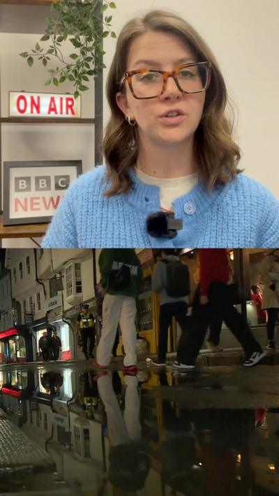 People walking down a street and a BBC reporter looks at the camera.