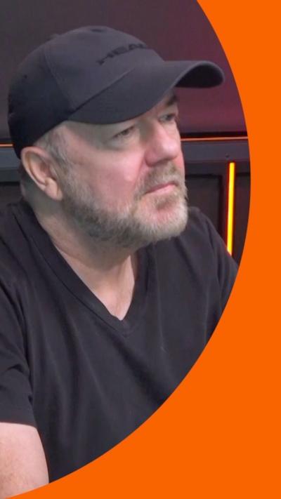 A man in a black hat and t-shirt talks to someone off-camera