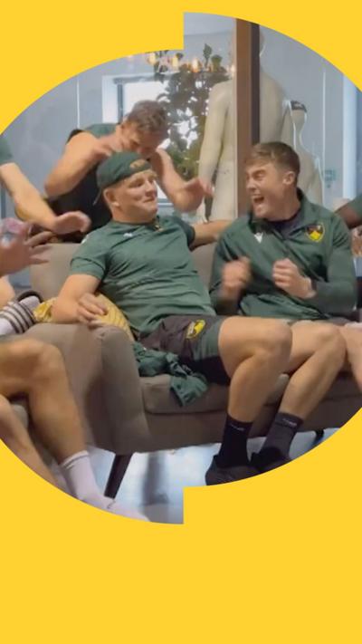 Northampton rugby players sat a sofa cheering