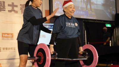 Elderly woman weightlifting wearing Santa hat