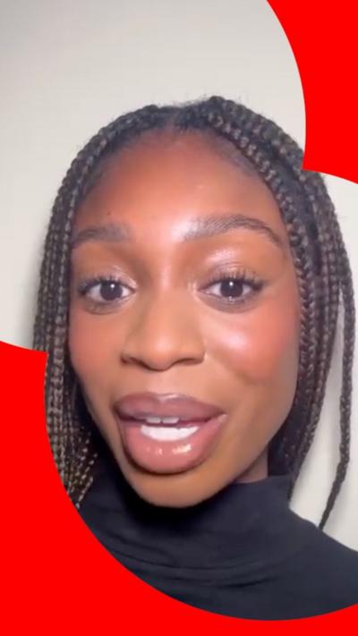 A woman with braids and a black turtle neck looks at the camera.