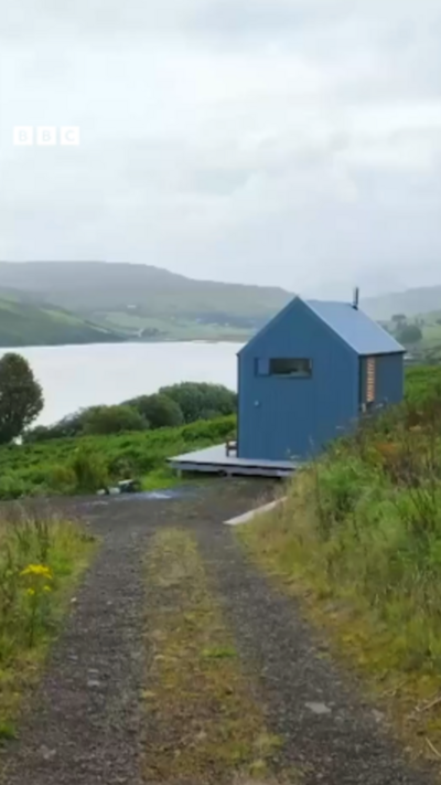 A small blue cabin overlooking a loch.