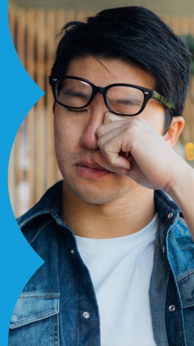 Man wiping eyes while lifting glasses