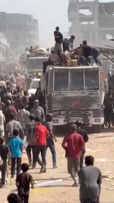 People on top of an aid truck, as others crowd around it