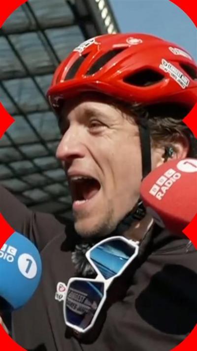 Greg James wearing a red helmet with a wide open mouth as he cheers