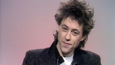 Bob Geldof sits in front of a pink background