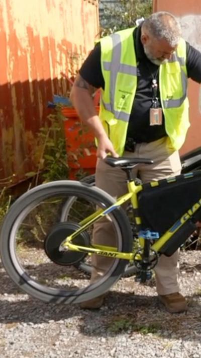 Man in hi-vis holding an illegal e-bike