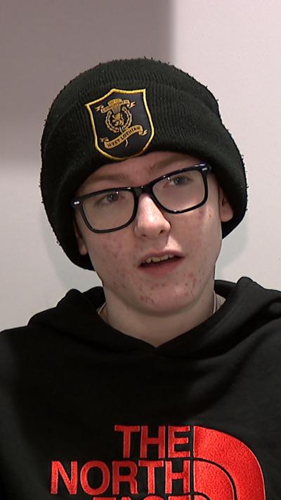 Young boy wearing black glasses, a black beanie, and a black North Face hoodie.