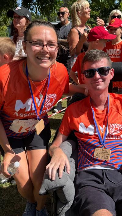 Craig and Ileshia Eskrett wearing training tops surrounded by support for the Run For MND