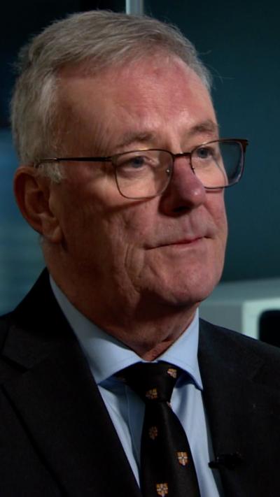 Mike Nesbitt is pictured wearing glasses, a dark jacket and tie